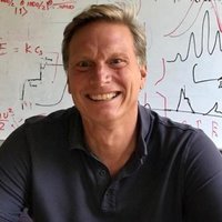 mark-kasevich Herzberg Mark Kasevich sitting in front of a whiteboard with black scribbles